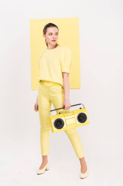 Retro boombox holding, uzağa arıyorsunuz ve arka plan üzerinde ilgi odağı ile poz şık kız