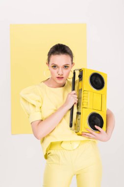Retro boombox holding, kameraya bakıyor ve arka plan üzerinde ilgi odağı ile poz şık kız