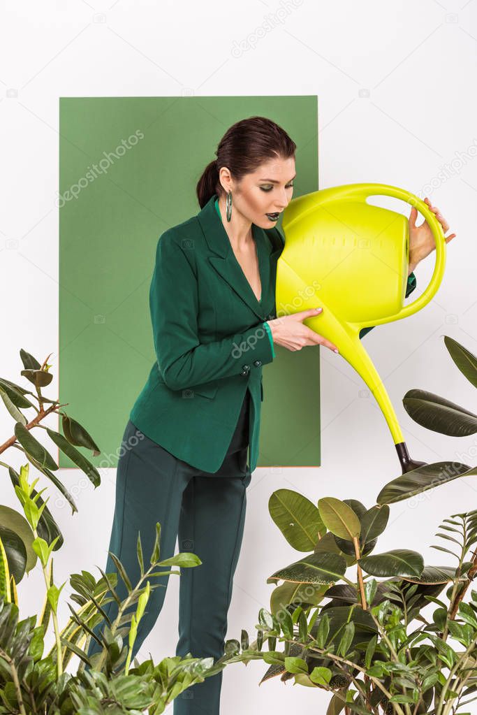 beautiful stylish woman watering plants and posing with sea green on background