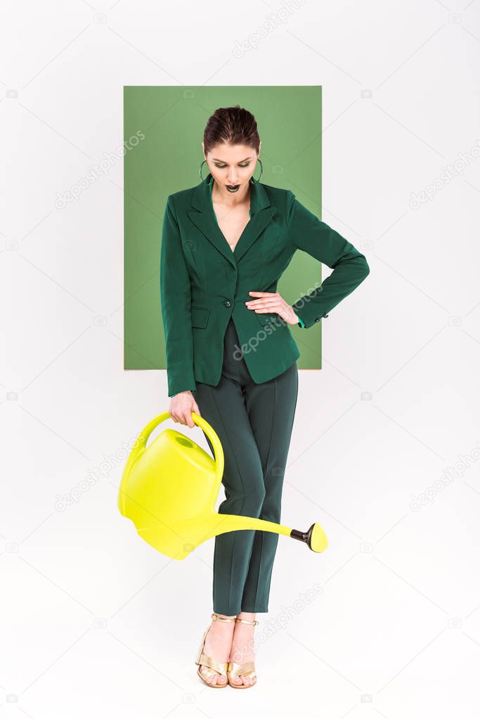 beautiful stylish woman holding watering can and posing with sea green and plants on background