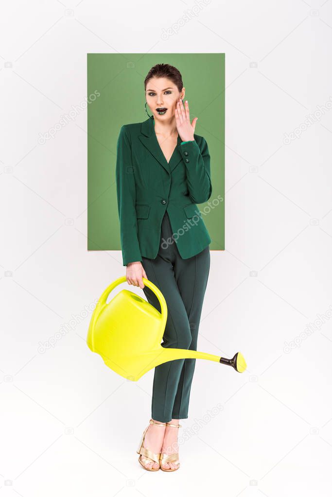 beautiful surprised woman holding watering can and posing with sea green and plants on background