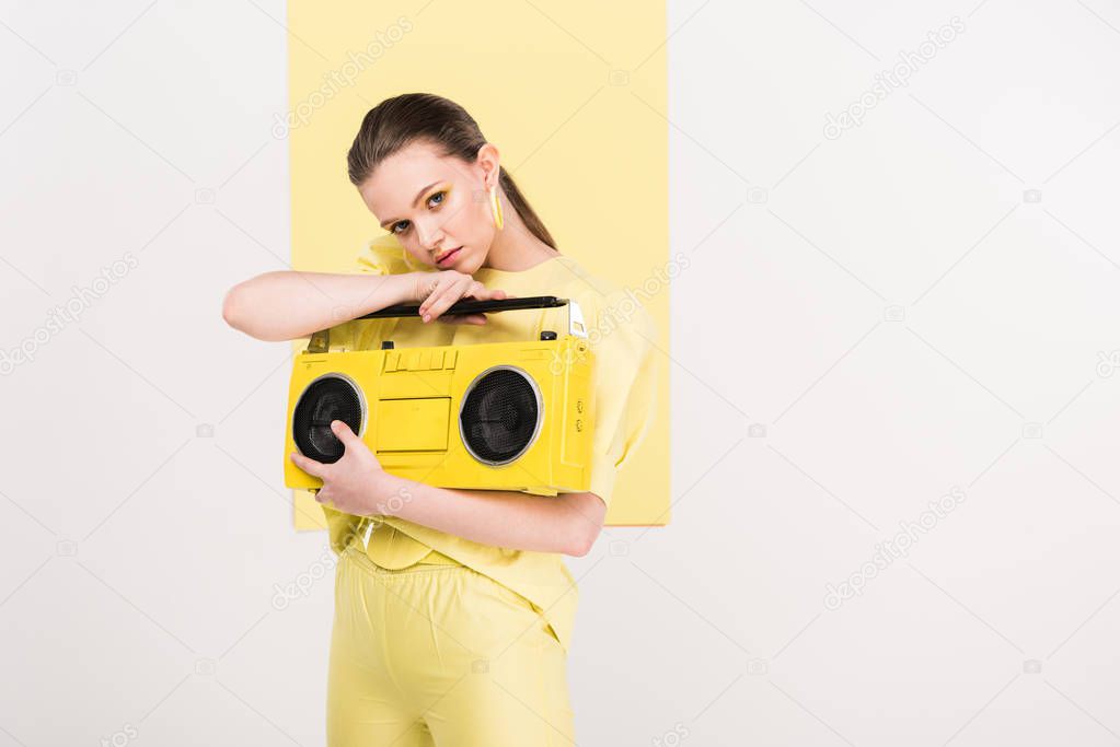 stylish girl holding retro boombox and posing with copy space and limelight on background