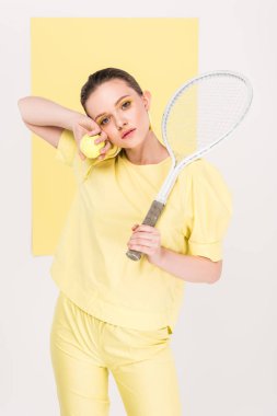 Tenis raketi ve arka plan üzerinde ilgi odağı ile poz kameraya bakarak topu ile güzel şık kız