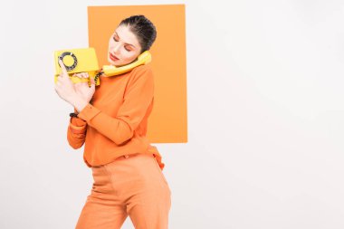 beautiful fashionable woman using retro telephone and posing with turmeric on background clipart