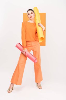 stylish young woman holding paper rolls, looking at camera and posing with turmeric on background clipart
