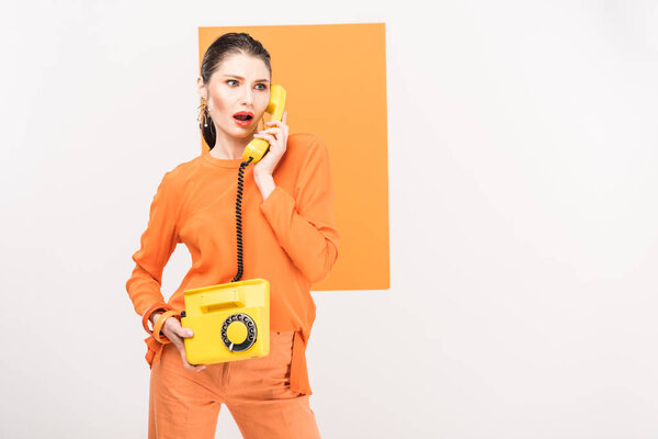 beautiful fashionable woman talking on retro telephone and posing with turmeric on background