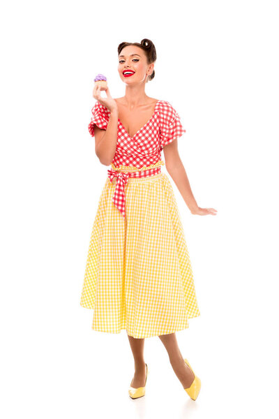 Pin up woman holding cupcace with purple cream while standing on high heels
