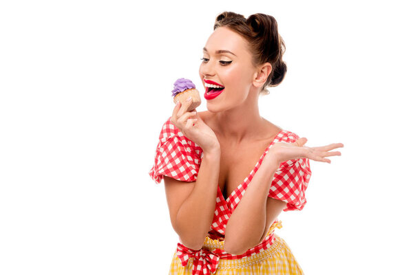 Pretty pin up girl tasting cupcake with purple cream isolated on white