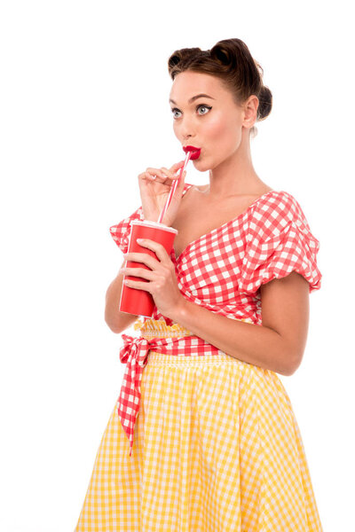 Pretty pin up girl drinking from red paper cup with straw isolated on white