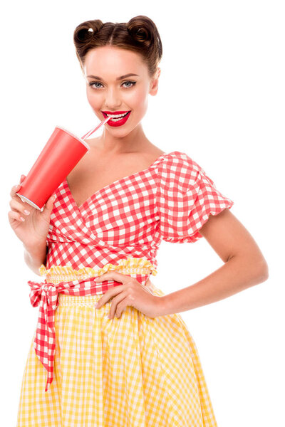 Smiling pin up girl drinking from paper cup with straw isolated on white