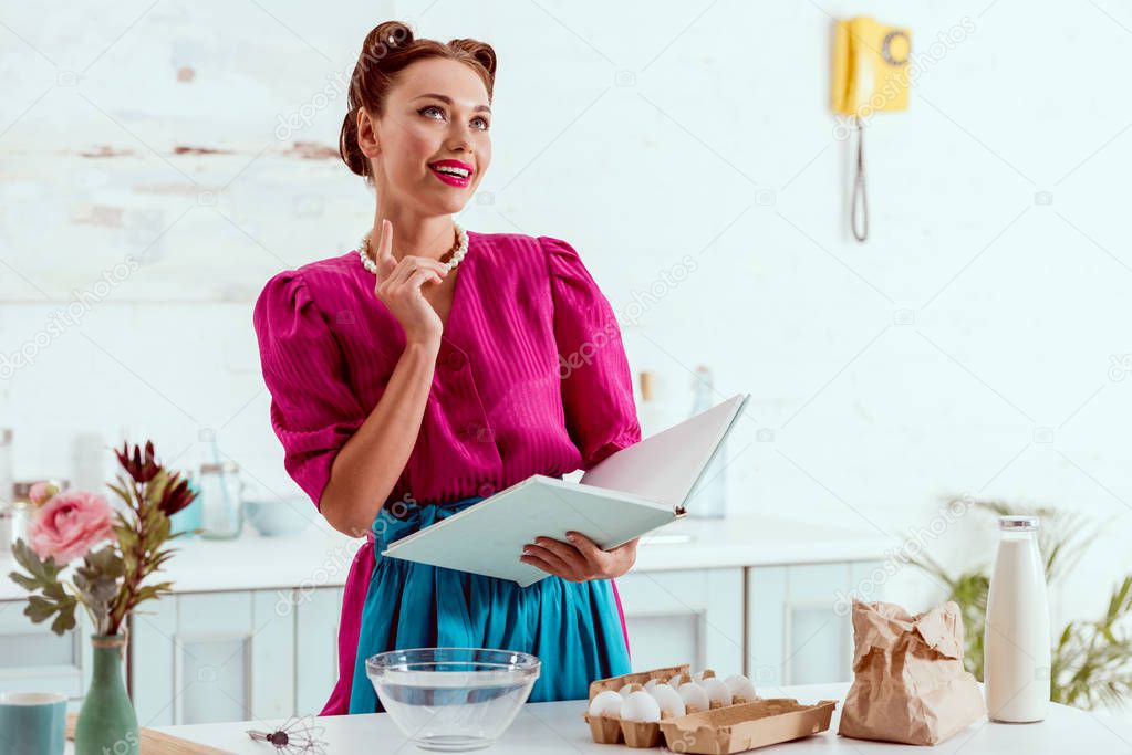 smiling pin up girl holding recipes book and showing idea sign