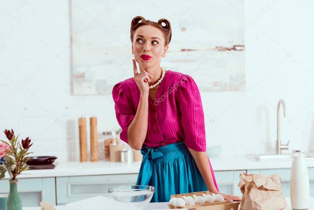 Pretty pin up girl standing by table with different ingredients and showing idea sign