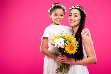 güzel mutlu anne ve kızı beyaz elbiseler ve çiçek buketi tutarak ve pink izole kamera gülümseyen çiçek çelenk 