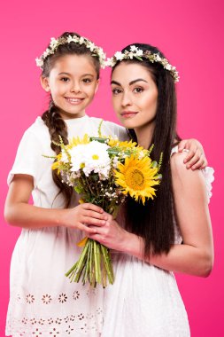 güzel mutlu anne ve kızı çiçek buketi tutarak ve pink izole kamera gülümseyen beyaz elbiseler 