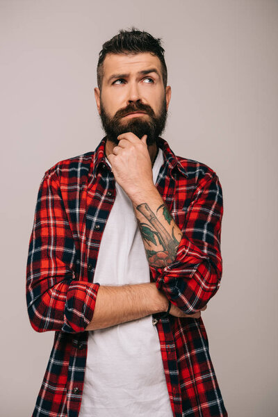 pensive bearded man in checkered shirt isolated on grey
