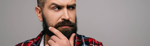suspicious bearded man in checkered shirt thinking isolated on grey