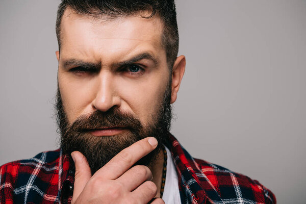 suspicious bearded man looking at camera isolated on grey