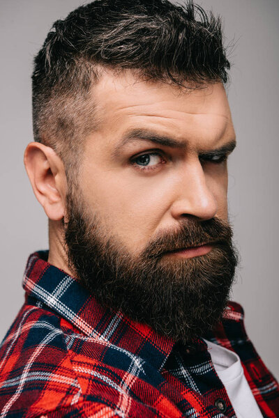 suspicious bearded man looking at camera isolated on grey