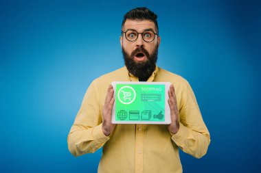 şok sakallı adam mavi izole app, alışveriş ile dijital tablet sunulması