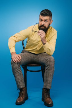 mavi izole sandalye üzerinde oturan yakışıklı sakallı adam