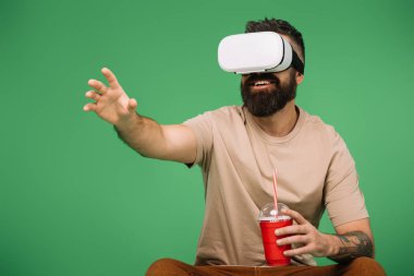 yeşil izole Vr kulaklık kullanarak soda ile gülümseyen adam