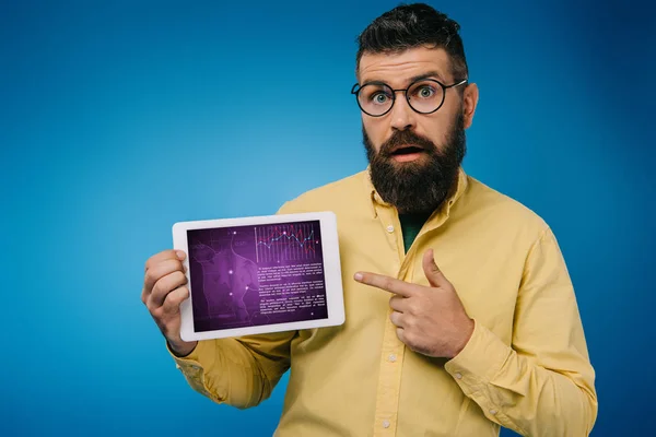 Zszokowany Brodaty Mężczyzna Wskazując Cyfrowy Tablet Infografikę Niebieskim Tle — Zdjęcie stockowe