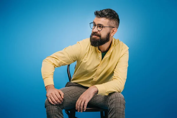 Bonito Homem Óculos Sentado Cadeira Isolado Azul — Fotografia de Stock