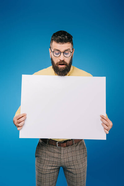 surprised man holding empty board isolated on blue