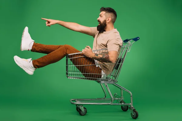 Excited Bearded Man Showing Something While Sitting Shopping Cart Isolated — Stock Photo, Image