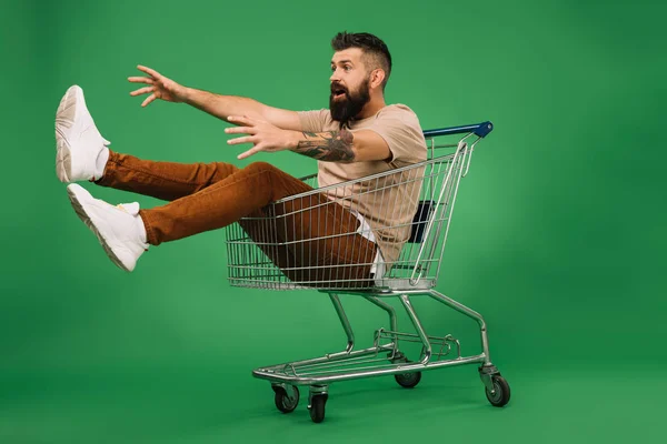 Excited Man Gesturing Sitting Shopping Cart Isolated Green — Stock Photo, Image