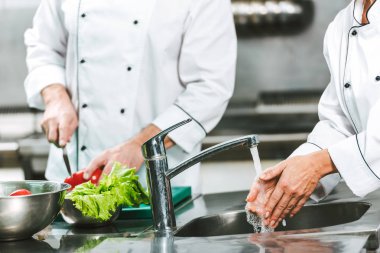 kadın şef meslektaşım arka planda lokanta mutfağı pişirme sırasında lavabo üzerinde el yıkama kırpılmış görünümünü