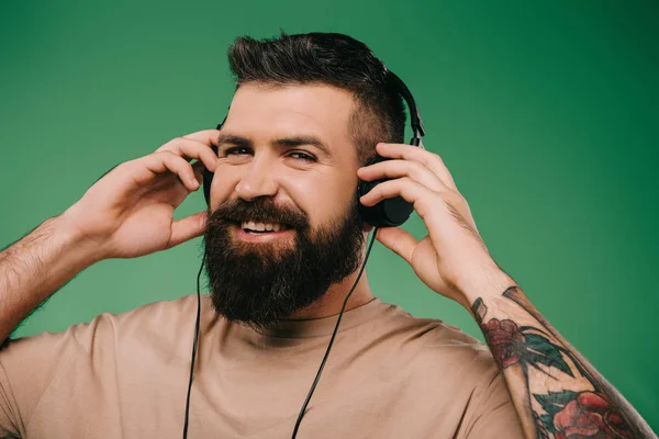 Χαμογελώντας Γενειοφόρος Άνδρας Ακούγοντας Μουσική Στα Ακουστικά Που Απομονώνονται Πράσινο — Φωτογραφία Αρχείου