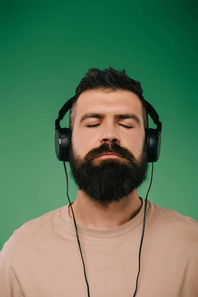 Бородатый Мужчина Закрытыми Глазами Слушает Музыку Наушниках Изолированы Зеленый — стоковое фото