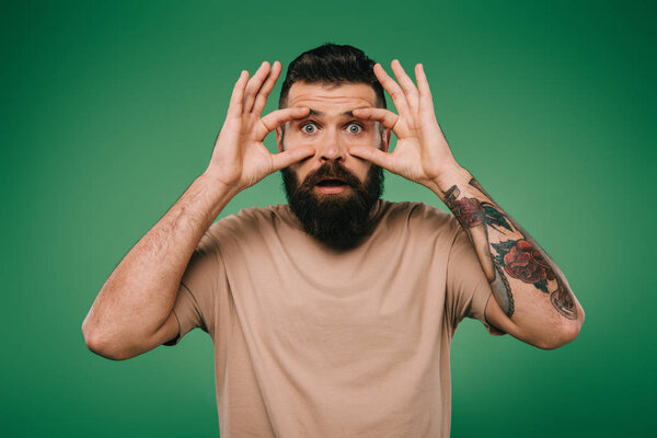 Красивый бородатый мужчина с открытыми глазами, изолированный от зеленого
