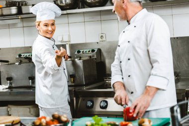 Restoran mutfağında yemek sırasında kruvaze ceketler, kadın ve erkek şefler 
