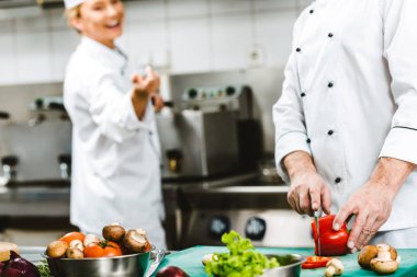 kruvaze ceketler, kadın ve erkek şefler görünümünü Restoran mutfağında yemek sırasında kırpılmış 