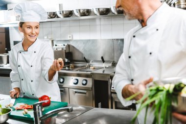 Restoran mutfağında yemek sırasında kruvaze ceketler, kadın ve erkek şefler 