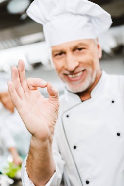tek tip kameraya görünümlü ve ok işareti Restoran mutfağında gösterilen yakışıklı gülümseyen erkek Şef