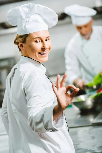 Hermosa Mujer Sonriente Chef Uniforme Sombrero Mirando Cámara Mostrando Signo — Foto de Stock