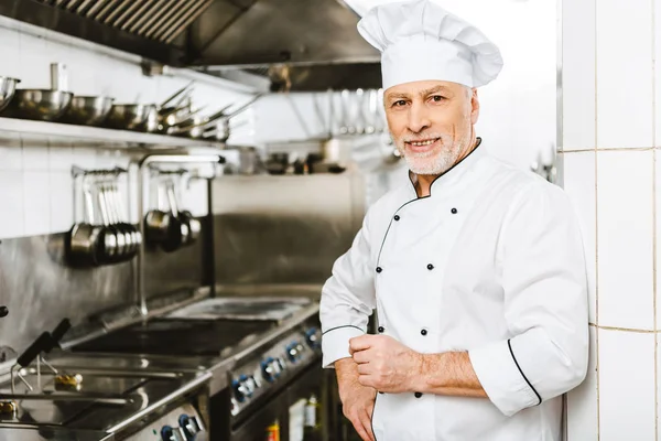 Bello Chef Maschio Sorridente Uniforme Cappello Guardando Fotocamera Nella Cucina — Foto Stock