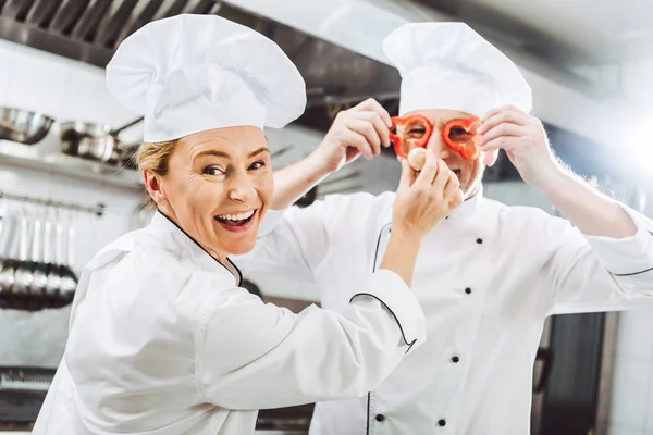 Cocinera Mirando Cámara Mientras Chef Masculino Sostiene Rodajas Pimienta Frente —  Fotos de Stock