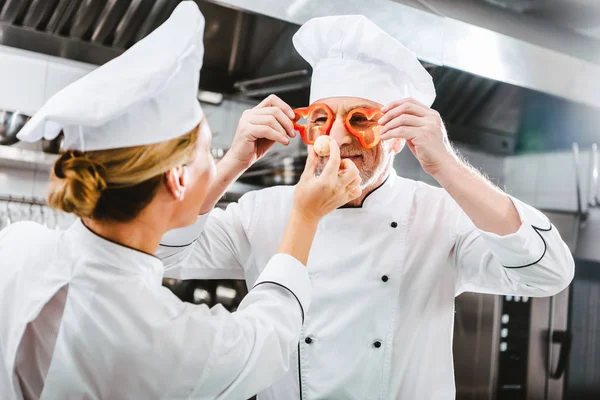 Cocinera Mirando Chef Masculino Sosteniendo Rodajas Pimienta Frente Cara Cocina —  Fotos de Stock