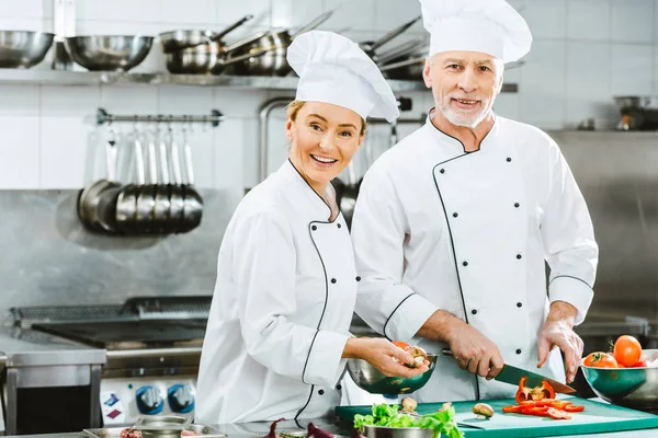 Kvinnliga Och Manliga Kockar Enhetlig Tittar Kameran Medan Skära Ingredienser — Stockfoto