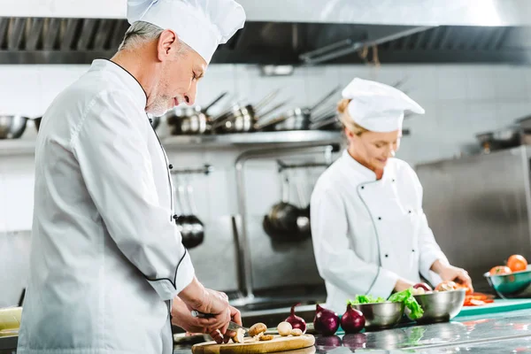 专注的男性和女性厨师在餐厅厨房统一烹饪 — 图库照片