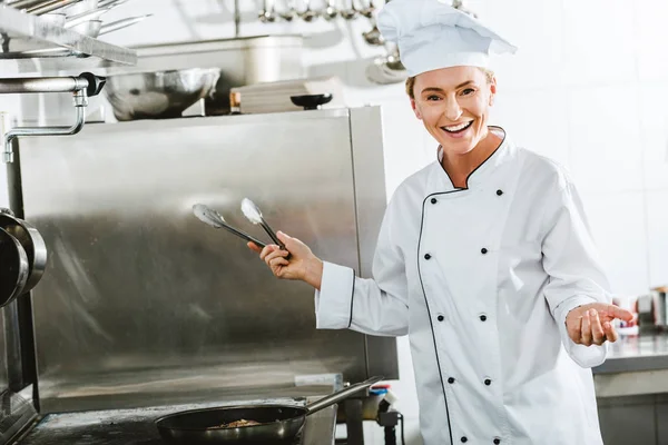 Hermosa Mujer Chef Uniforme Usando Pinzas Cocina Mientras Cocina Cocina — Foto de Stock