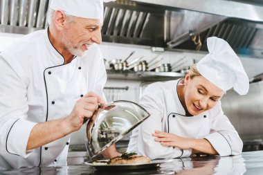 et yemek için Restoran mutfakta kadın aşçı Tepsi hizmet üzerinde sunulması üniformalı erkek Şef