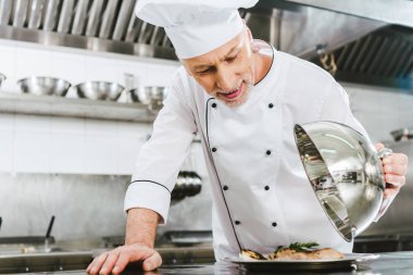 seçici odak kubbe et yemek restoran mutfak ile tepsi hizmet tutan üniformalı yakışıklı erkek Şef