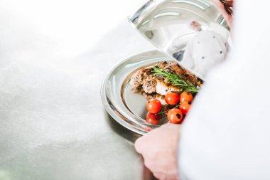 Erkek aşçı tepsi et yemek lokanta mutfağı ile hizmet kubbe tutarak kısmi görünümünü