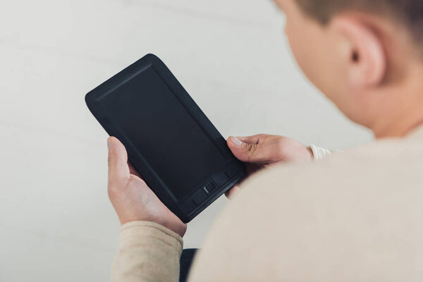 selective focus of man holding ebook with blank screen