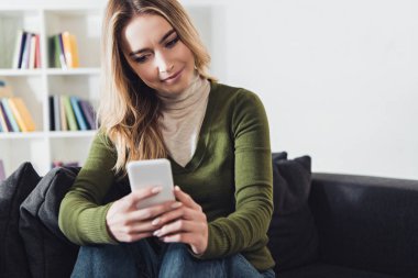 evde otururken kadın kadın holding smartphone gülümseyen